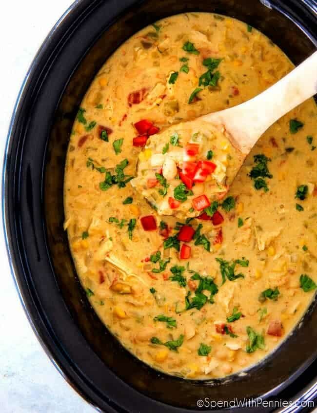 Overhead shot of White Chicken Chili in a black crockpot with a wooden spoon