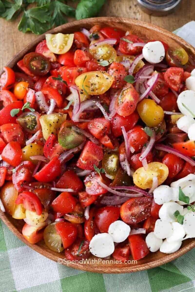 tomato salad on a wood plate with fresh herbs