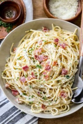 Spaghetti carbonara in a bowl with a fork and spoon